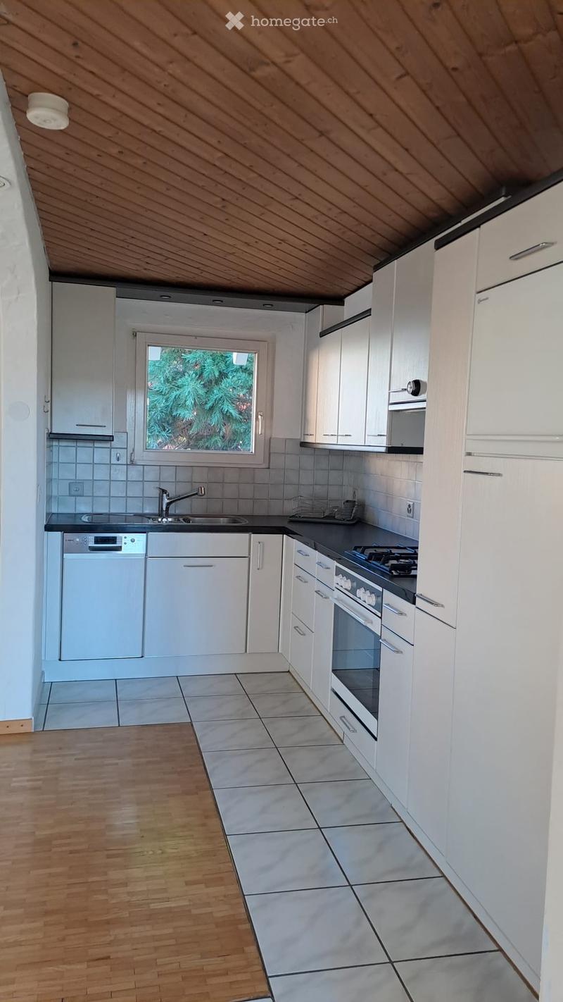 Modern kitchen with white cabinets, stainless steel appliances, wooden flooring, and tiled backsplash.