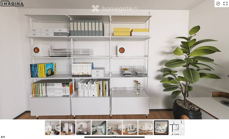 A modern, minimalist room with a white bookshelf filled with books and decorative items, a potted plant, and a small table with cups.