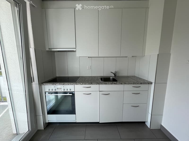 Modern kitchen with white cabinets, granite countertop, built-in oven, and stainless steel sink.
