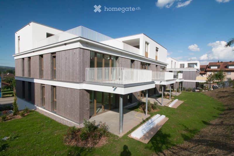 Modern two-story house with a combination of white and wood siding, large windows, and multiple balconies.