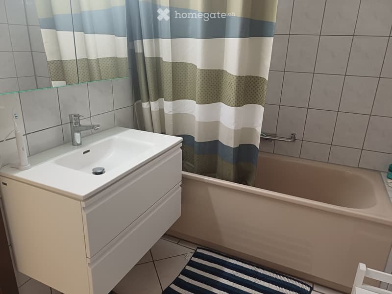 Modern bathroom with a white sink, faucet, mirror, bathtub, and a striped shower curtain.