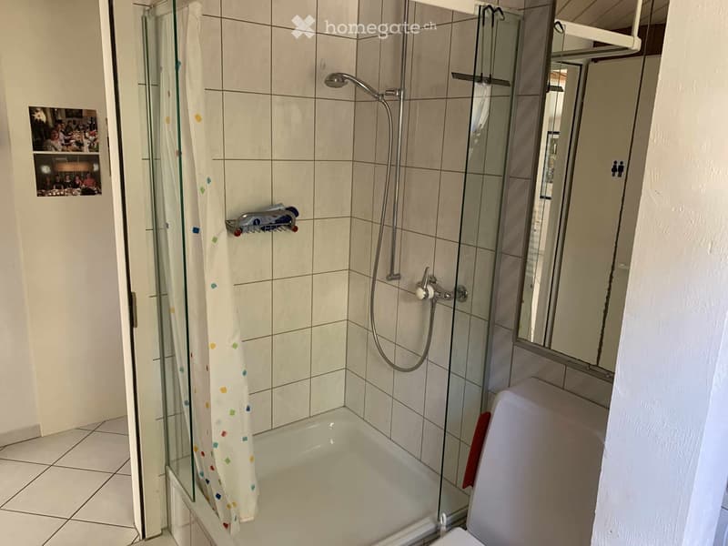 Bathroom with a bathtub, glass-enclosed shower, tiled walls, and a towel hanging on the side.