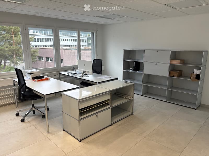 Office space with desks, chairs, laptops, computer monitors, cabinets, and shelves.