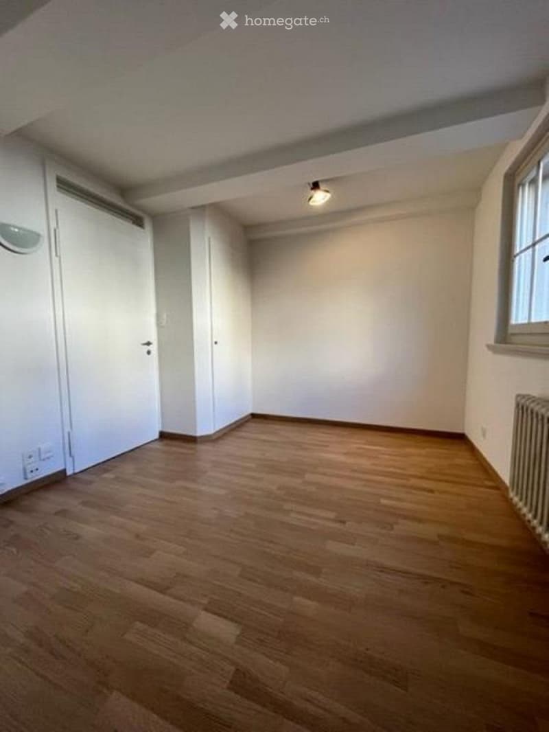 Empty room with wooden flooring, white walls, and a single window. No furniture or equipment is present.