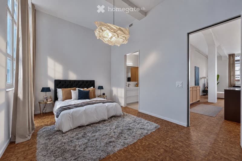 Modern bedroom with a large bed, shaggy rug, nightstands, table lamps, and a pendant light. The room features wooden flooring and large windows with curtains.