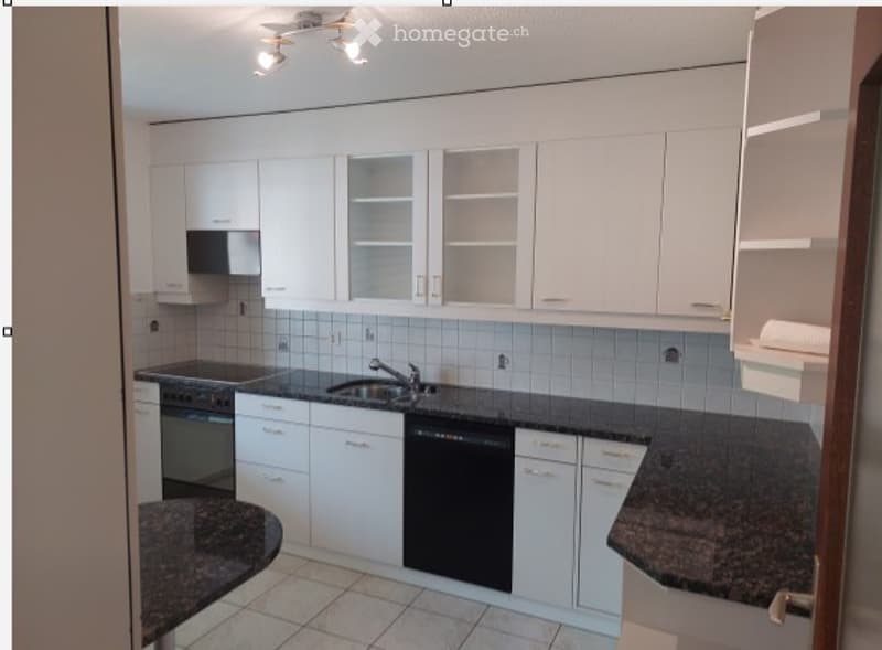 Modern kitchen with white cabinets, granite countertops, and stainless steel appliances including a sink, oven, and dishwasher.