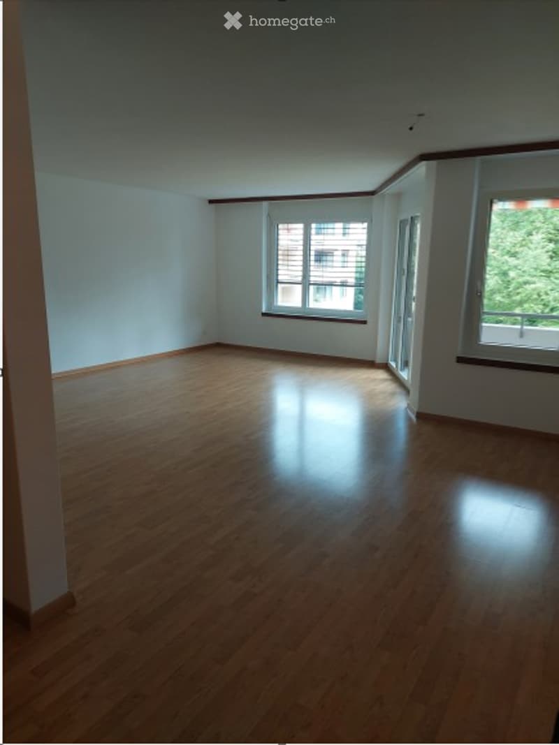 Empty room with wooden flooring, white walls, and large windows with blinds. No furniture or equipment present.
