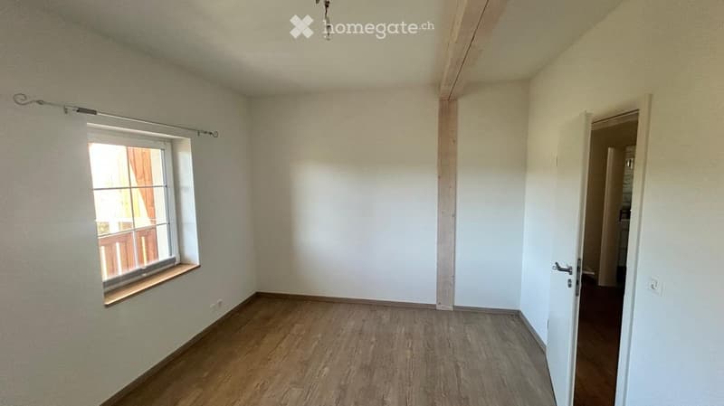 Empty room with wooden flooring, white walls, and a window with a wooden sill. No furniture or equipment present.