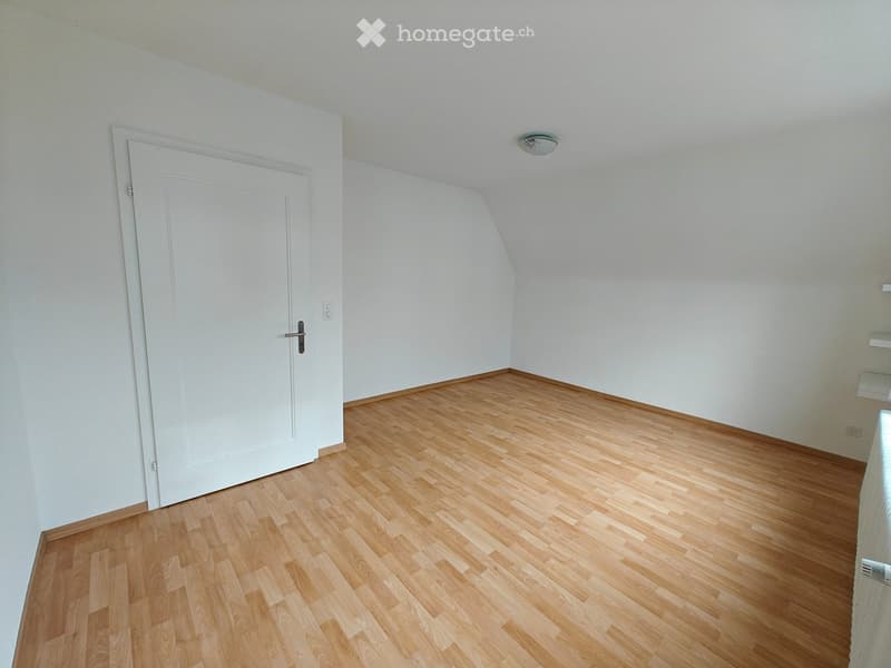 Empty room with wooden flooring, white walls, and a white door. No furniture or equipment is present.