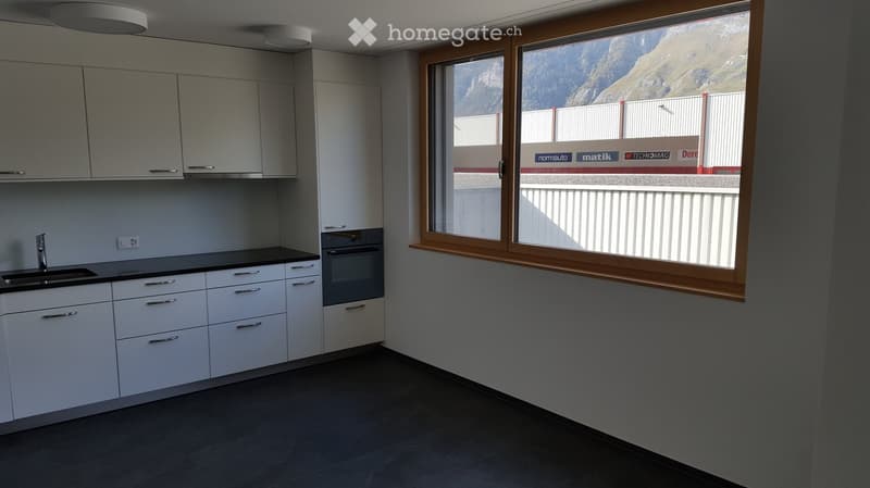 Modern kitchen with white cabinets, a sink, and an oven, featuring large windows with a scenic mountain view.