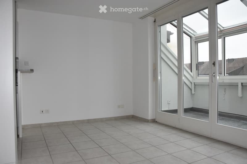Empty room with tiled floor, white walls, and large glass doors leading to a balcony area.