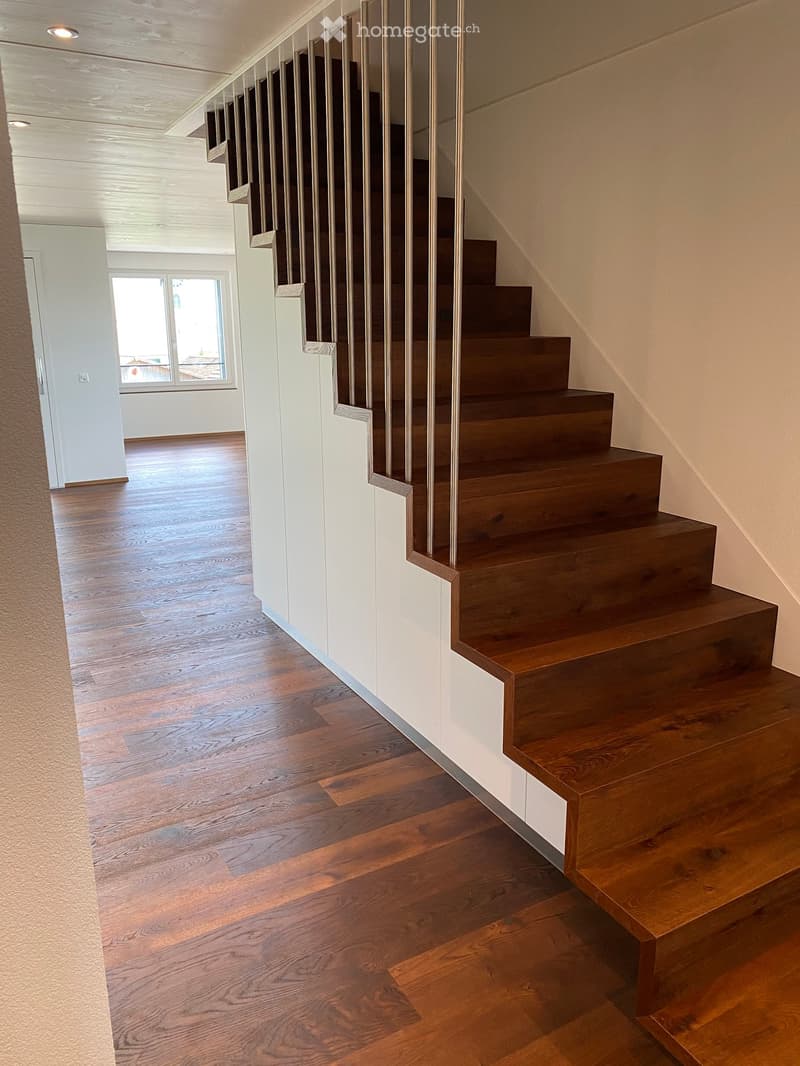 Wooden staircase with metal railing, hardwood flooring, white walls, and recessed lighting.