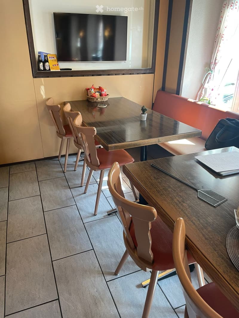 A furnished room with a table, chairs, a sofa, a screen, and a small basket on the table.