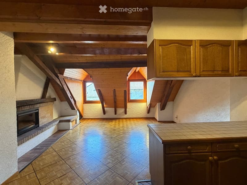 A cozy, well-lit room with wooden beams, a fireplace, and built-in cabinets. The space features a tiled floor and large windows allowing natural light to fill the room.