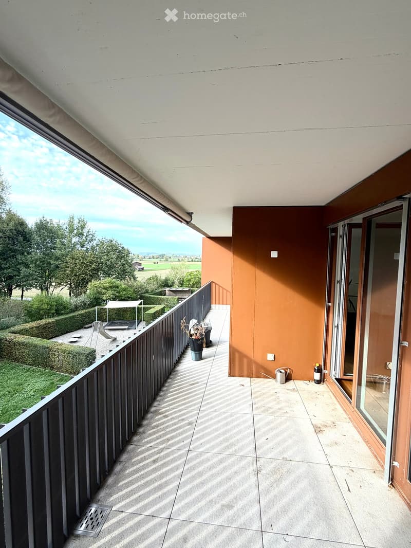Balcony with tiled floor, wooden railing, and scenic countryside view.