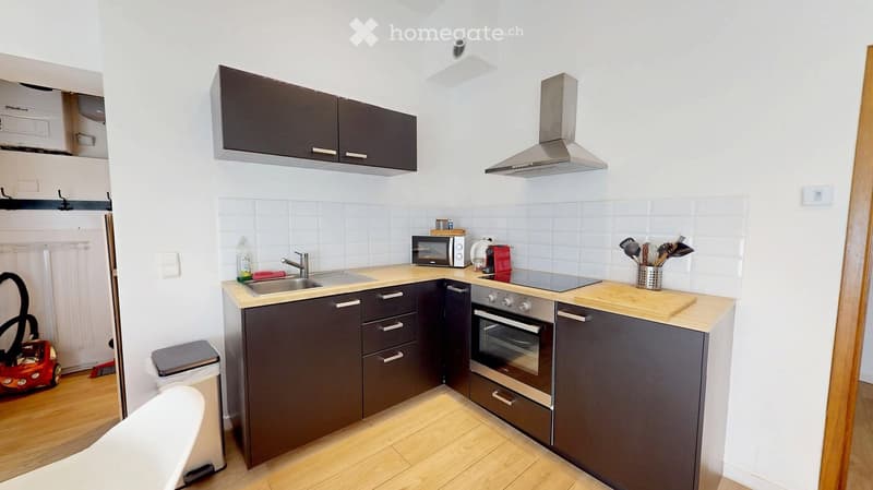 Modern kitchen with dark grey cabinets, stainless steel appliances, wooden countertops, and a sink with a faucet. Includes a microwave, coffee maker, and various kitchen utensils.