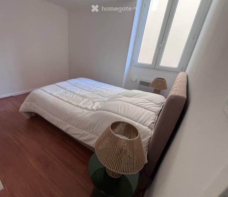 Cozy bedroom with a large bed, two table lamps, and wooden flooring.