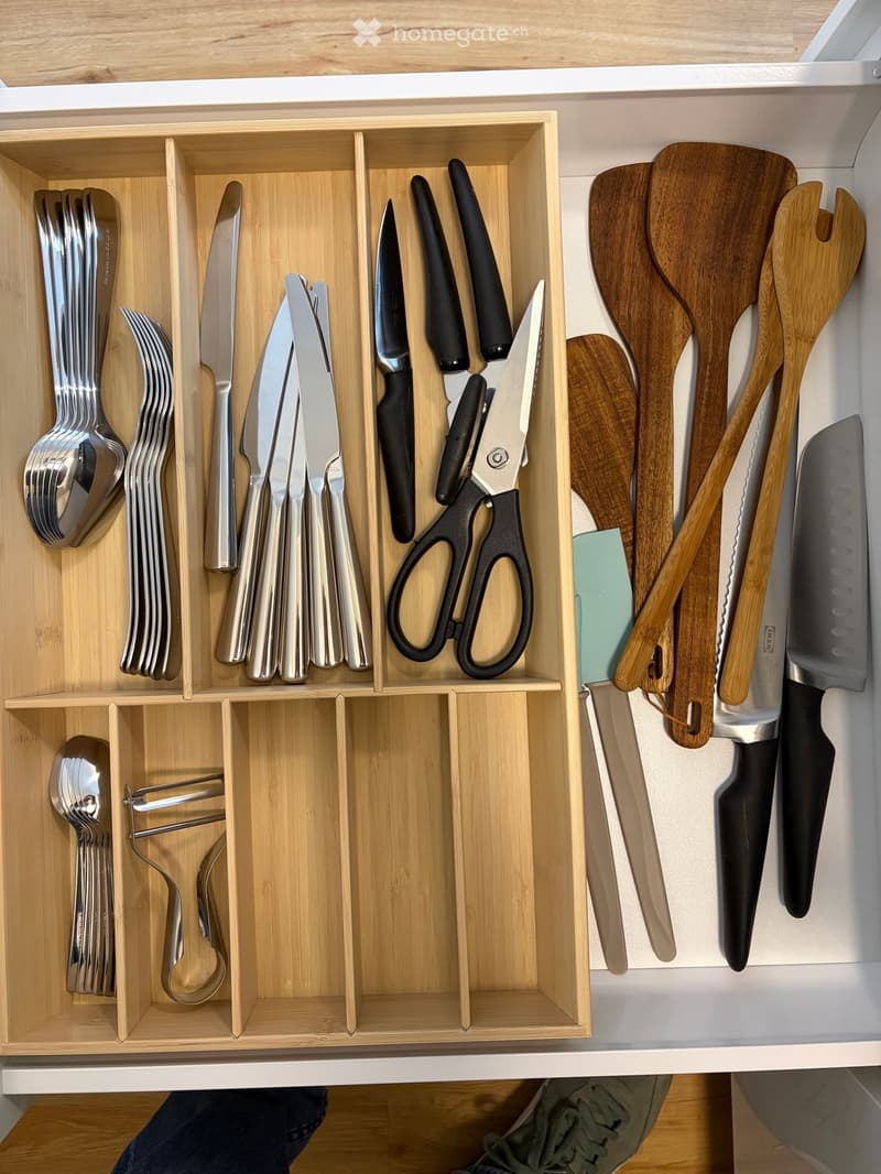 Wooden drawer containing silverware, cutlery, and kitchen tools