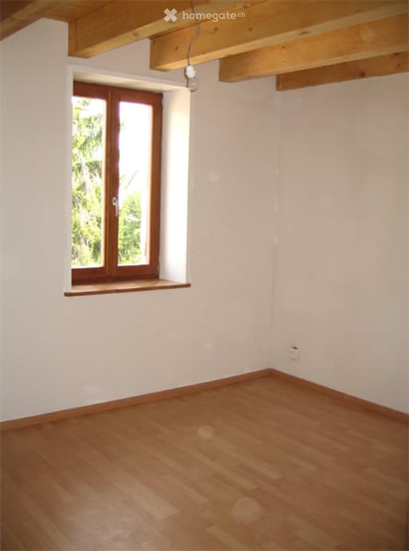 Empty room with wooden flooring, white walls, and a single window with wooden frame and sill.