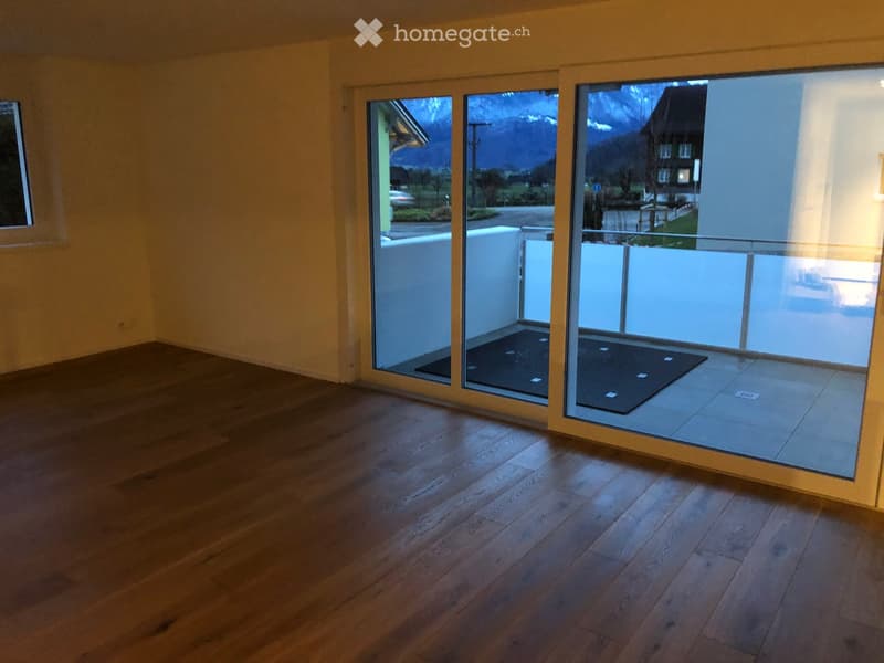 Empty room with wooden flooring and large sliding glass doors leading to a balcony or terrace. The space is unfurnished, with no visible furniture or equipment.