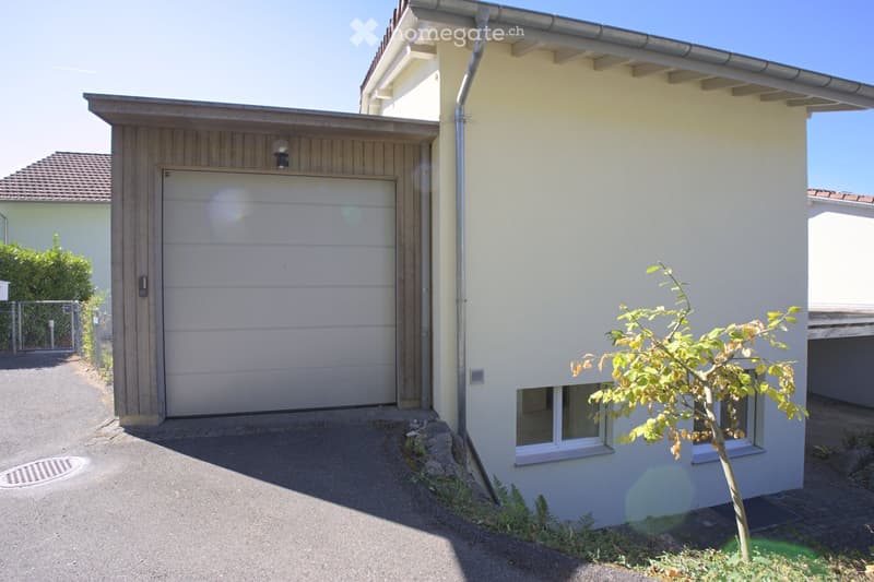 Single-story house with a garage, light yellow exterior, and small garden area.