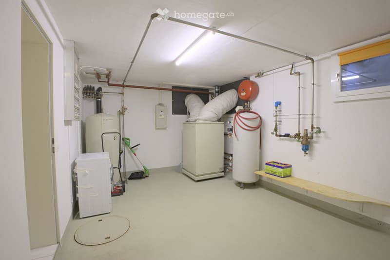Utility room with water heater, boiler, storage unit, bench, and cleaning tools.