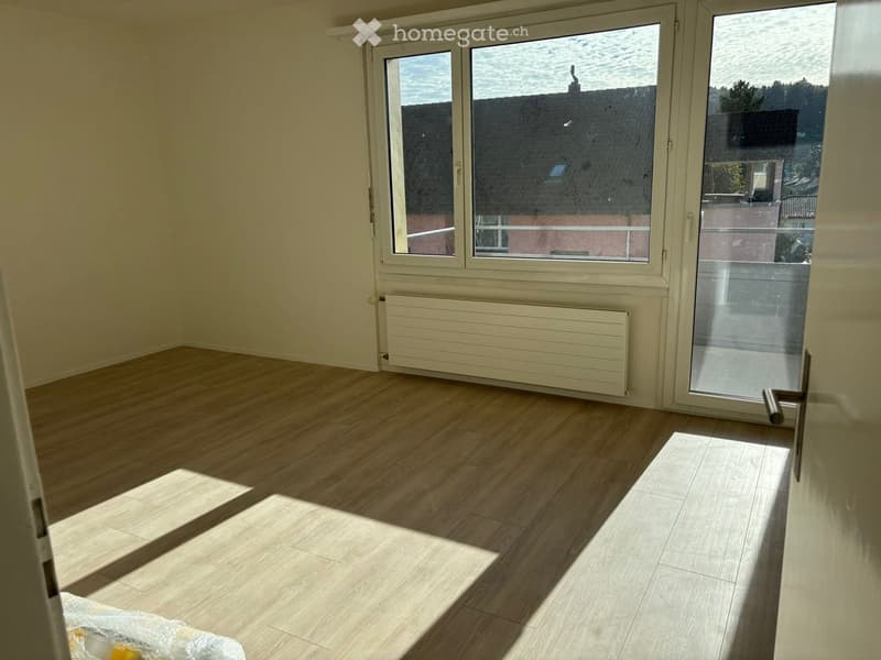 Empty room with wooden floor, large windows, balcony view