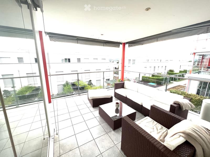 Balcony with tiled floor, glass railing, and outdoor furniture including a sofa, coffee table, and chairs.