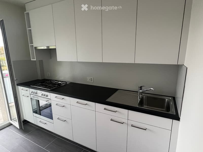 Modern kitchen with white cabinets, black countertops, a built-in stove, oven, and sink.