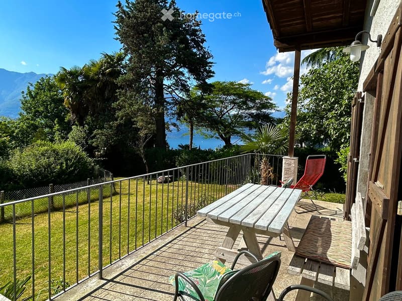 Balcony with wooden table, chairs, and scenic mountain view.