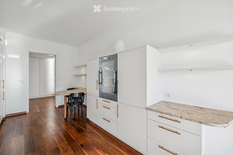 modern kitchen, white cabinetry, marble countertop, stainless steel appliance, wooden floor, small table, black chairs