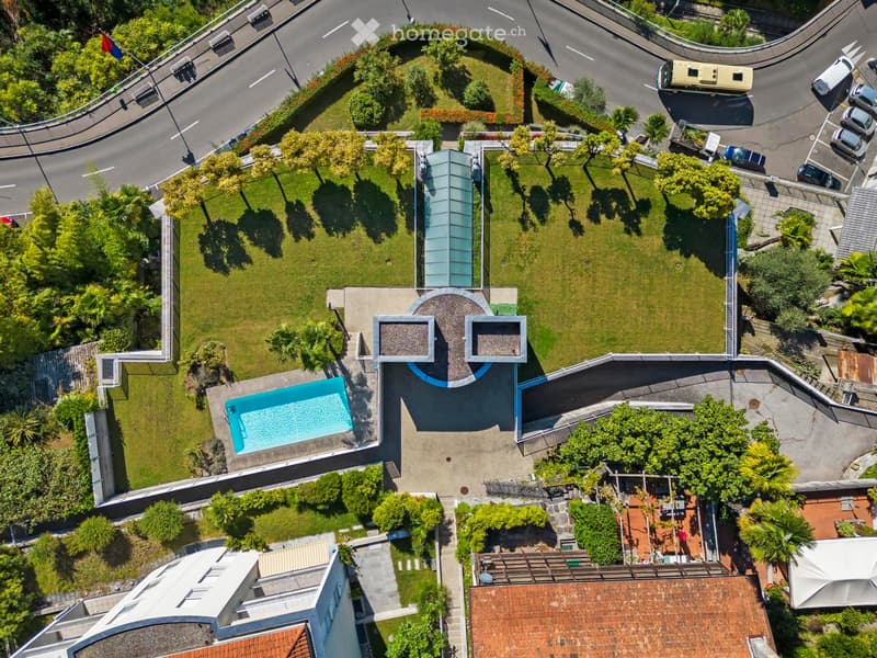 Modern house with swimming pool, located in a residential area with parking, lush greenery