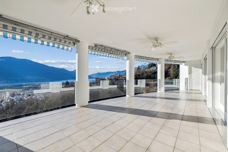 covered terrace with glass railings, view of mountains and city