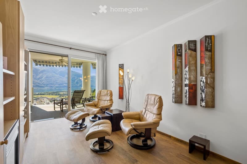 large sliding doors leading to balcony, hardwood floor, beige leather chairs, wooden ottoman, wall art, side table, power outlet