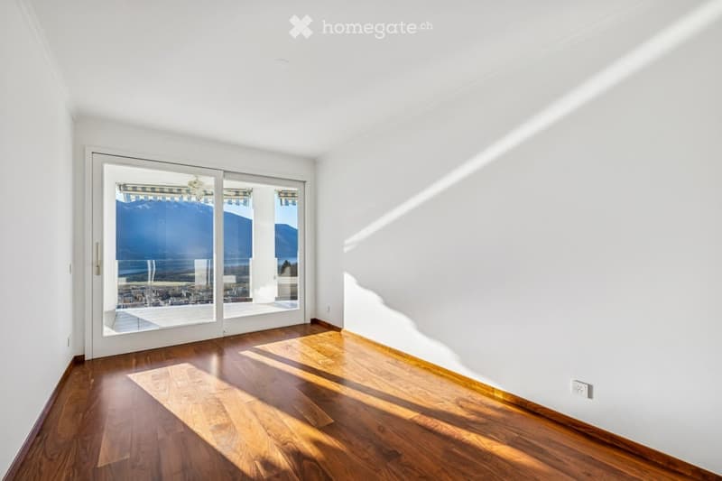 Spacious room with large glass sliding doors, hardwood floors, white walls, and power outlet.