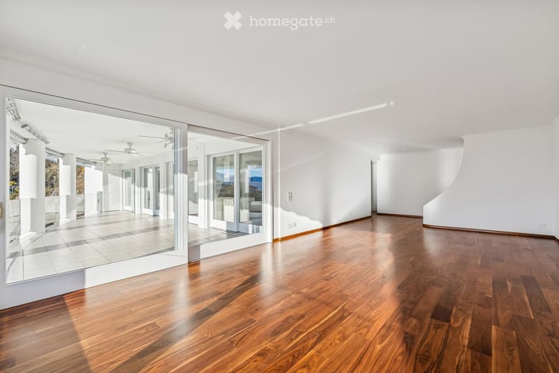 Wide glass doors leading to a balcony, hardwood floor, large windows, bright lighting, empty room