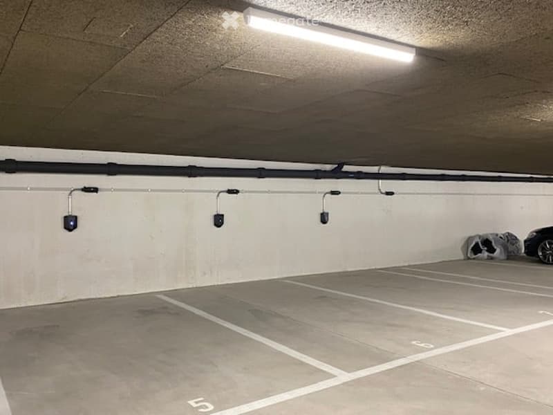 underground parking lot, white walls, grey floor, white markings, ceiling light, 3 parking spots
