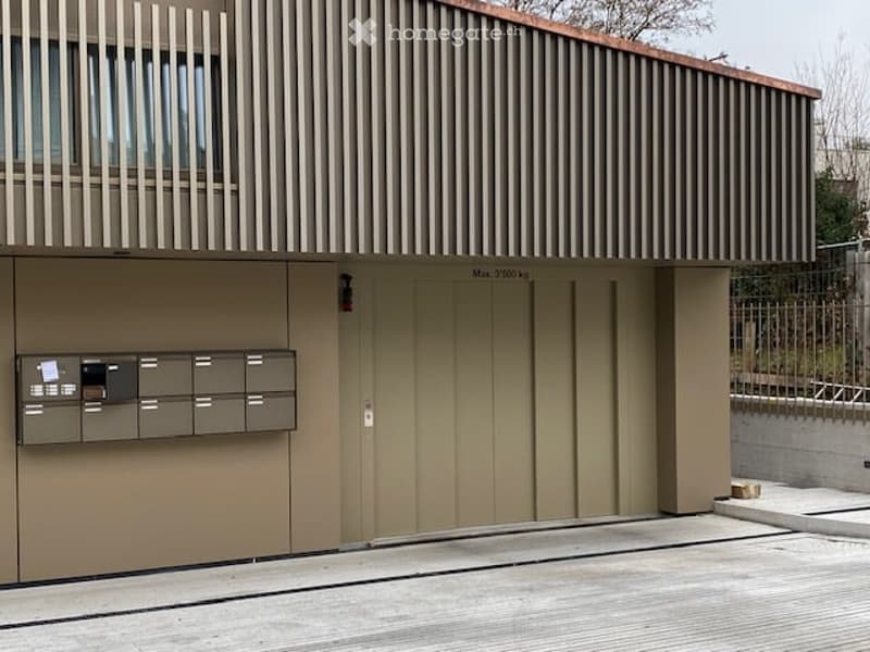 A building with a garage entrance, metal railings, and a row of mailboxes.