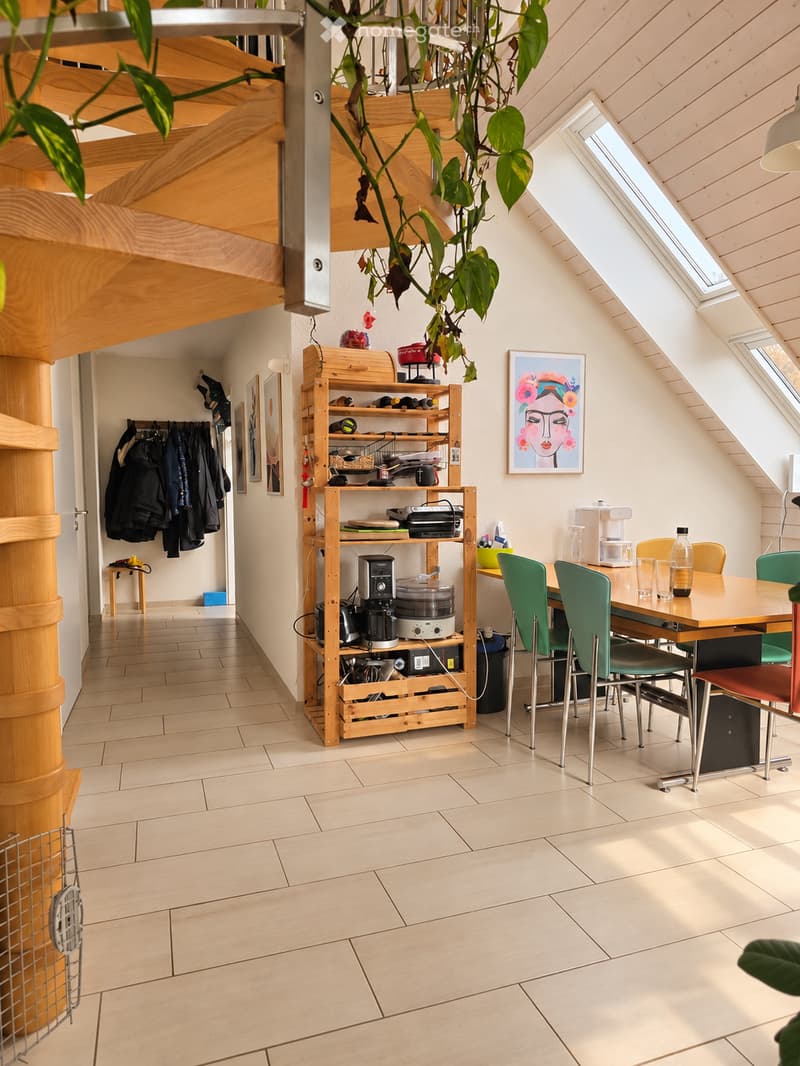 Bright, open kitchen and dining area with wooden shelves, a dining table with chairs, and a coffee maker on the counter.