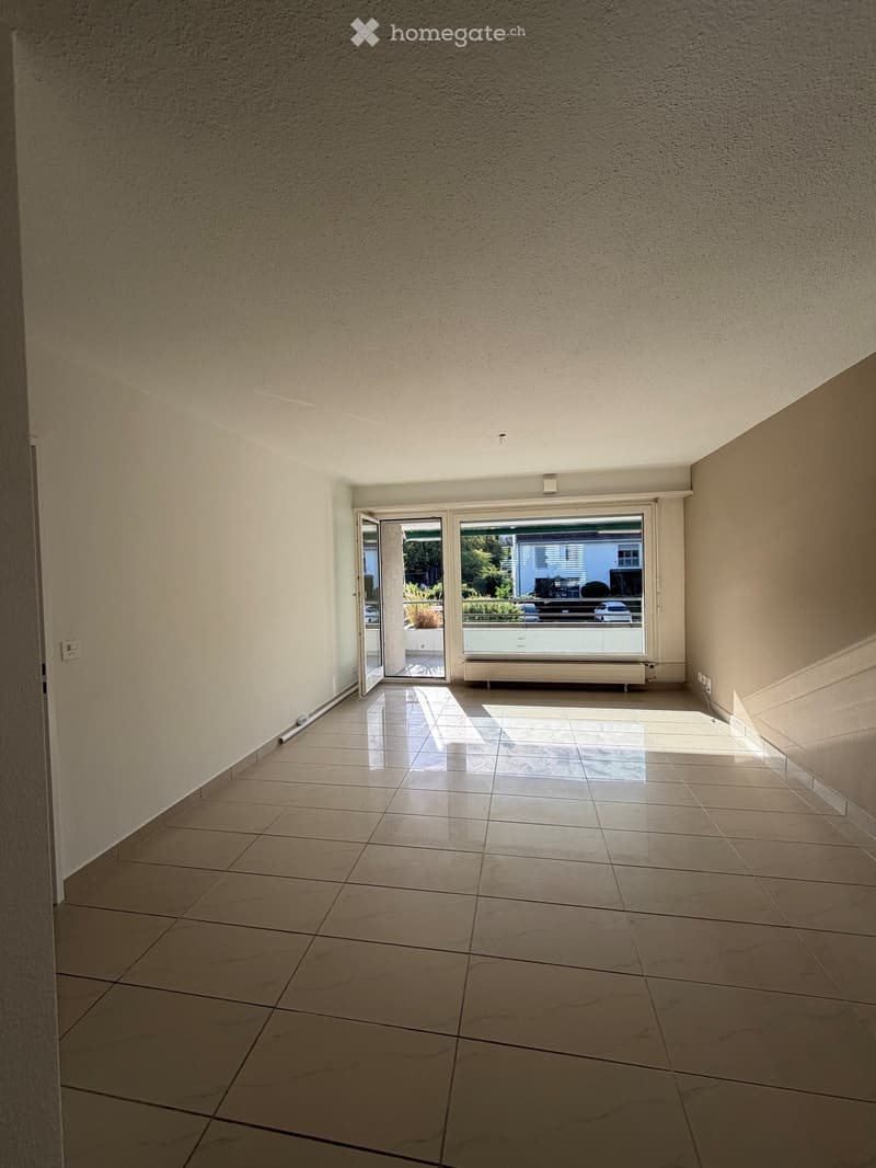 Empty room with tiled floor, white walls, and large sliding glass doors leading to a balcony or outdoor area.