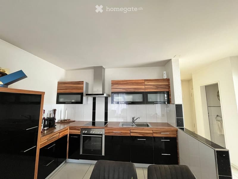 Modern kitchen with wooden and black cabinetry, stainless steel appliances, and a central island with a sink and stove.