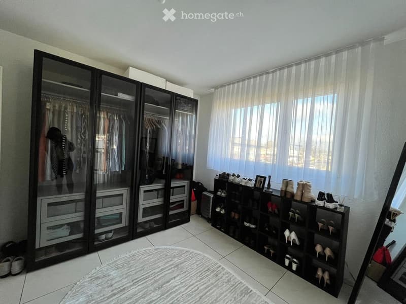 Well-lit walk-in closet with large mirrored wardrobe, shoe rack, and various accessories.