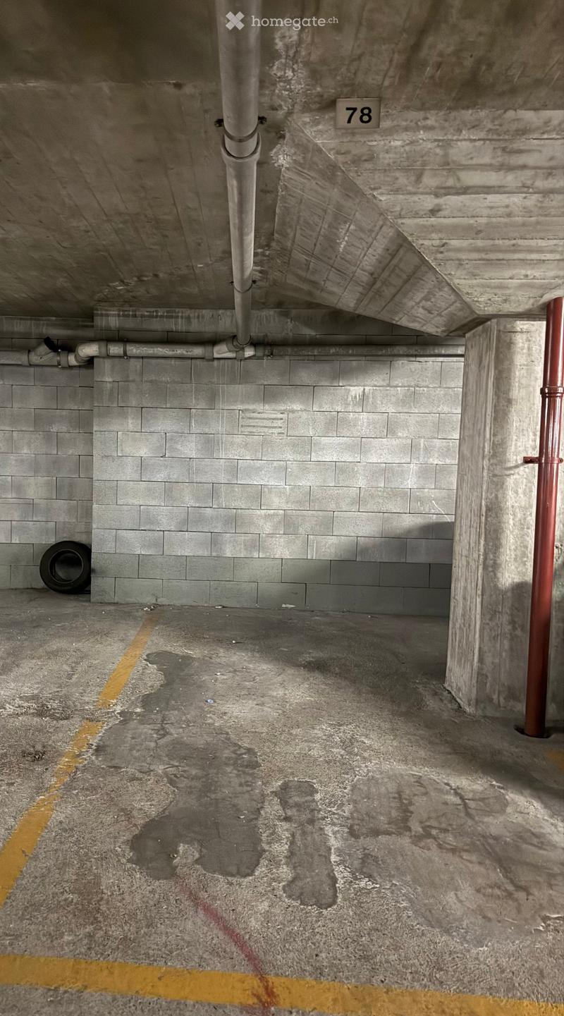 Underground garage with concrete walls, floor markings, and a single tire visible.