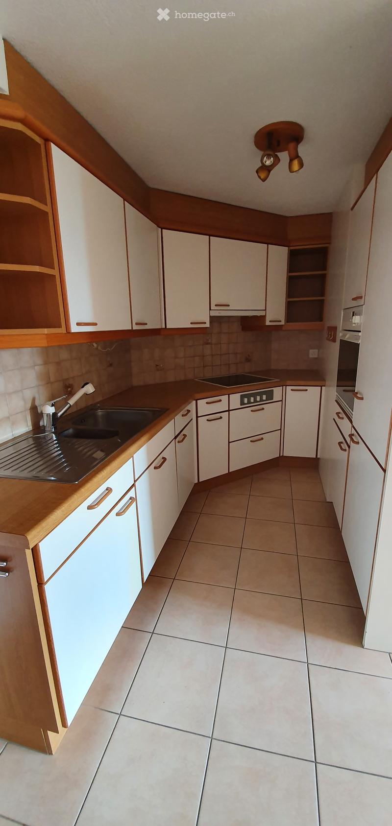 Modern kitchen with white cabinets, wooden countertops, tiled floor, sink, stove, and oven.