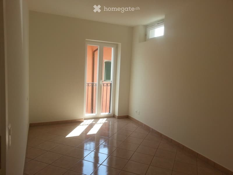 empty room with sliding doors, balcony, white walls, brown tiles