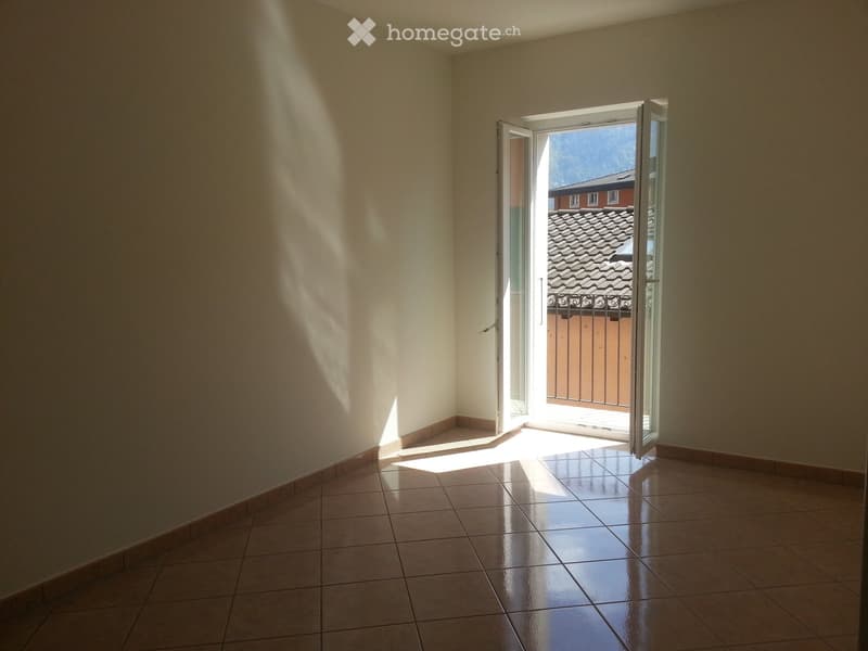 empty room with white walls, open sliding door, tile flooring, balcony