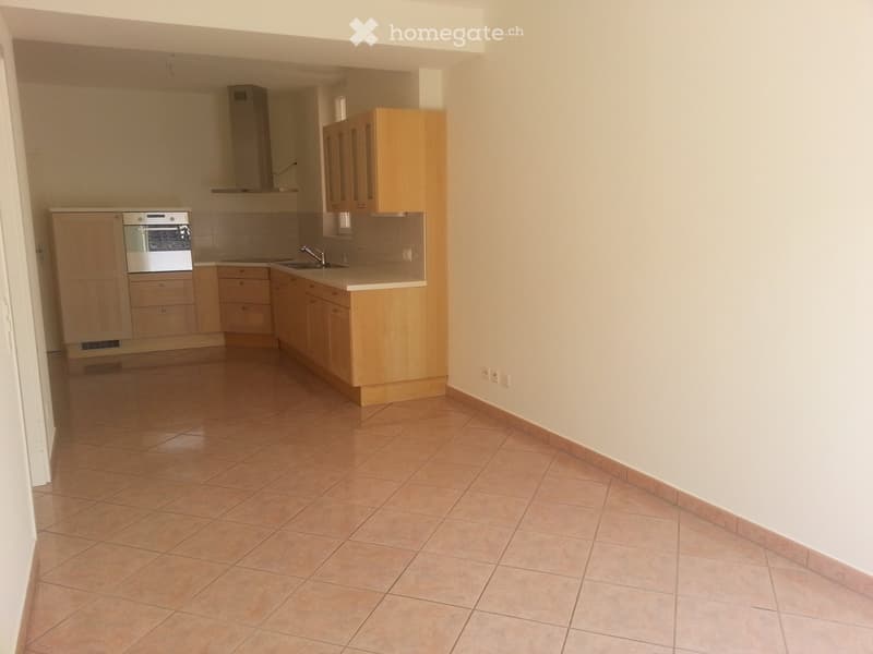 Empty kitchen with wooden cabinets, tile flooring, and modern appliances, including a built-in oven and a sink.