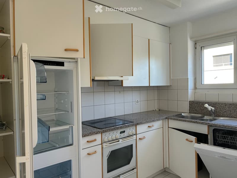 Modern kitchen with white cabinets, granite countertops, stainless steel appliances including a refrigerator, oven, and dishwasher, and a window with blinds.
