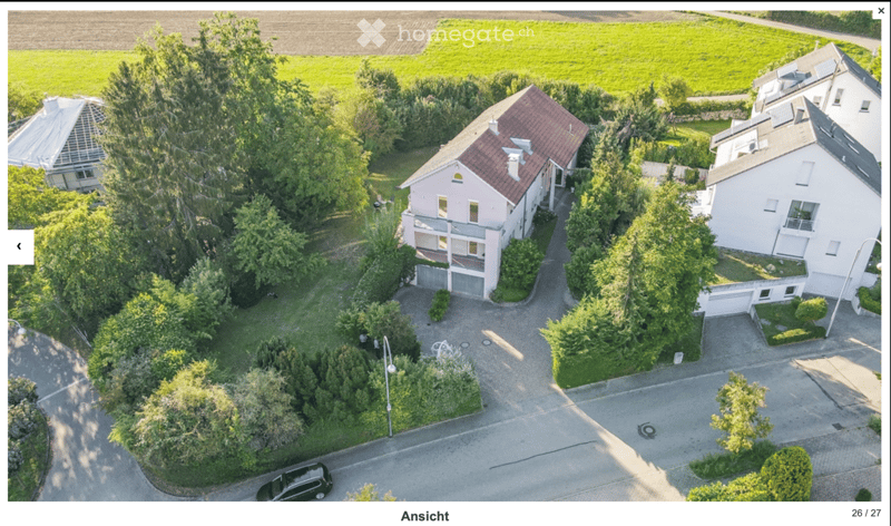 Aerial view of a residential area with multiple houses, driveways, and surrounding greenery.