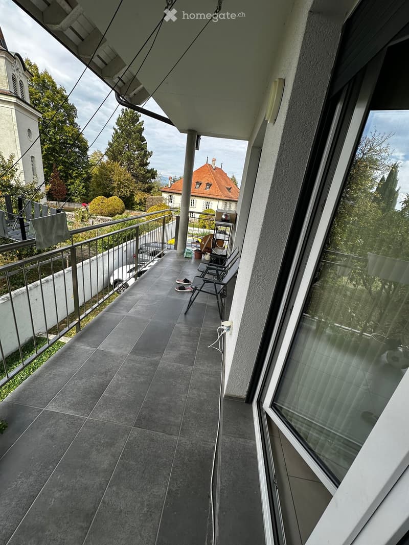 Balcony with tiled floor, metal railing, and a small table and chair set.